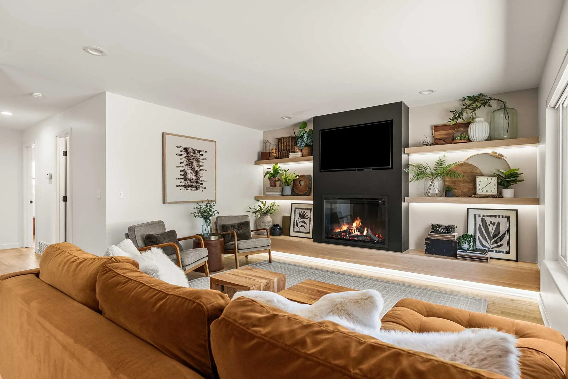 Stylish den showcasing black fireplace, TV cabinet with greenery, beige seating, designed by Make the Room, interior decorators.