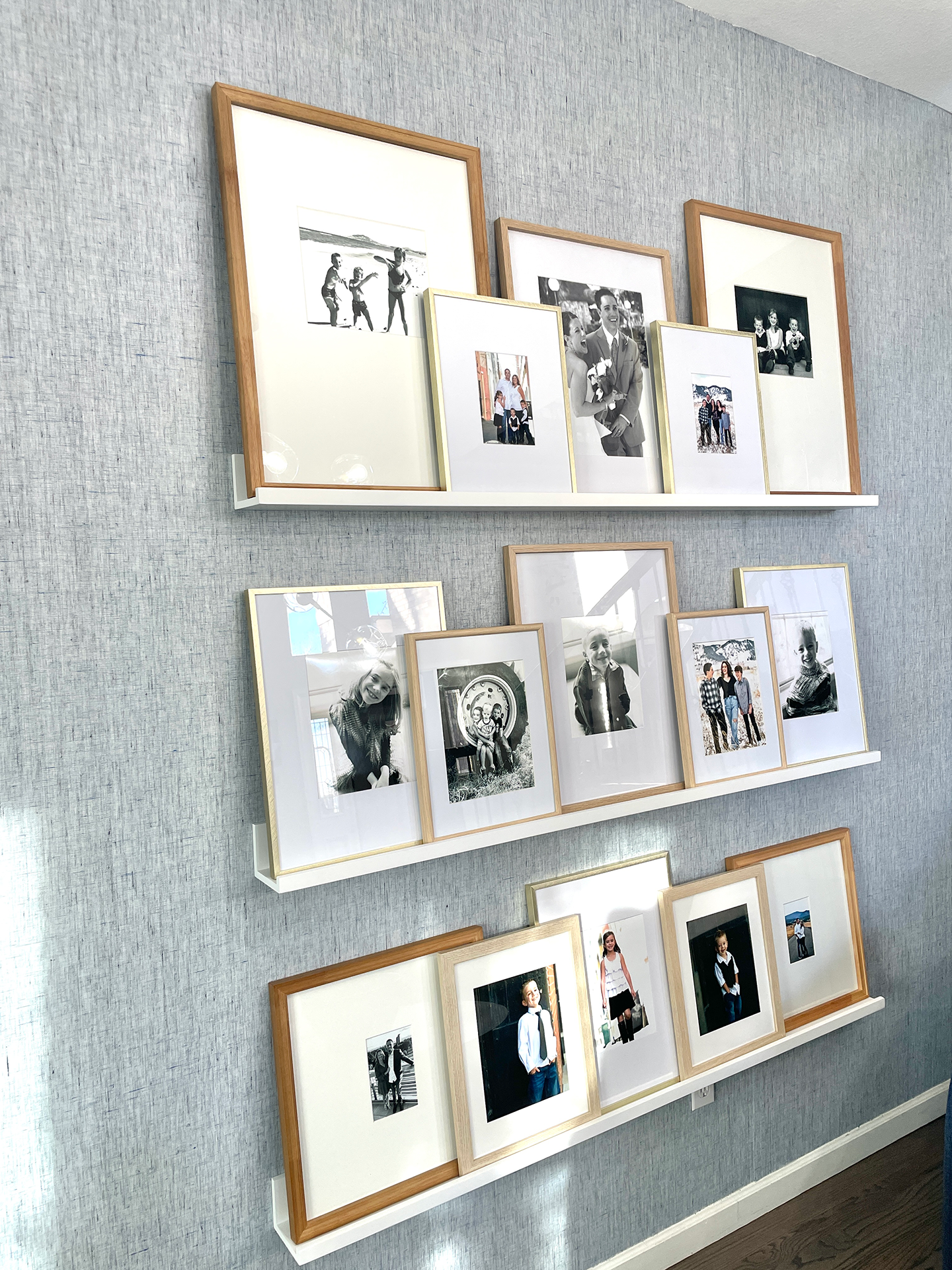 Stylish arrangement of framed portraits on white shelves against gray wallpaper, as designed by Make The Room