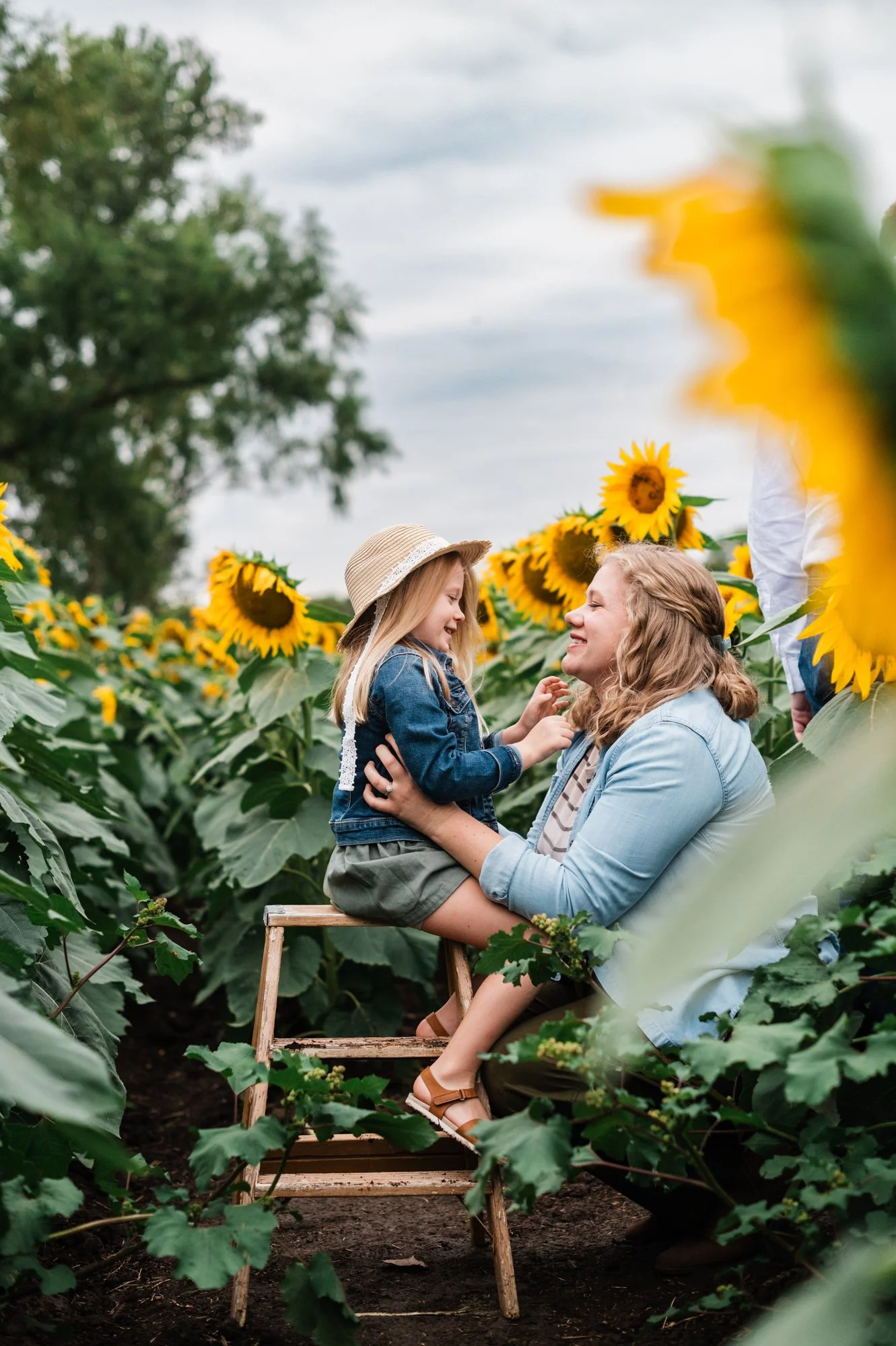 A mom & daughter enjoying a sunny day in a sunflower field. 