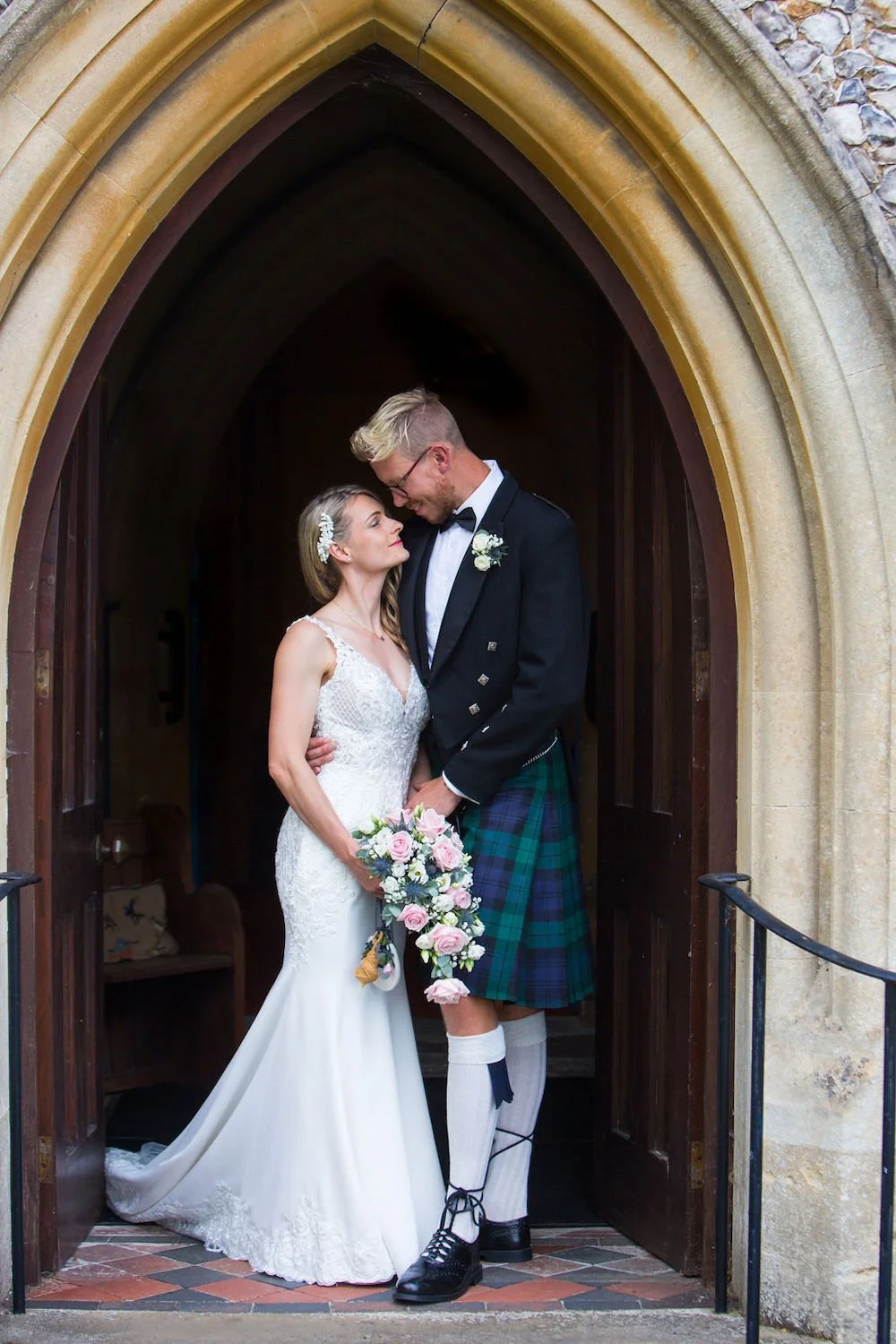 Church wedding, wedding photographer, capturing bride and groom walking outside for wedding portraits, groom in kilt, bride in wedding dress with yellow wedding flowers and button holes, Surrey weddings