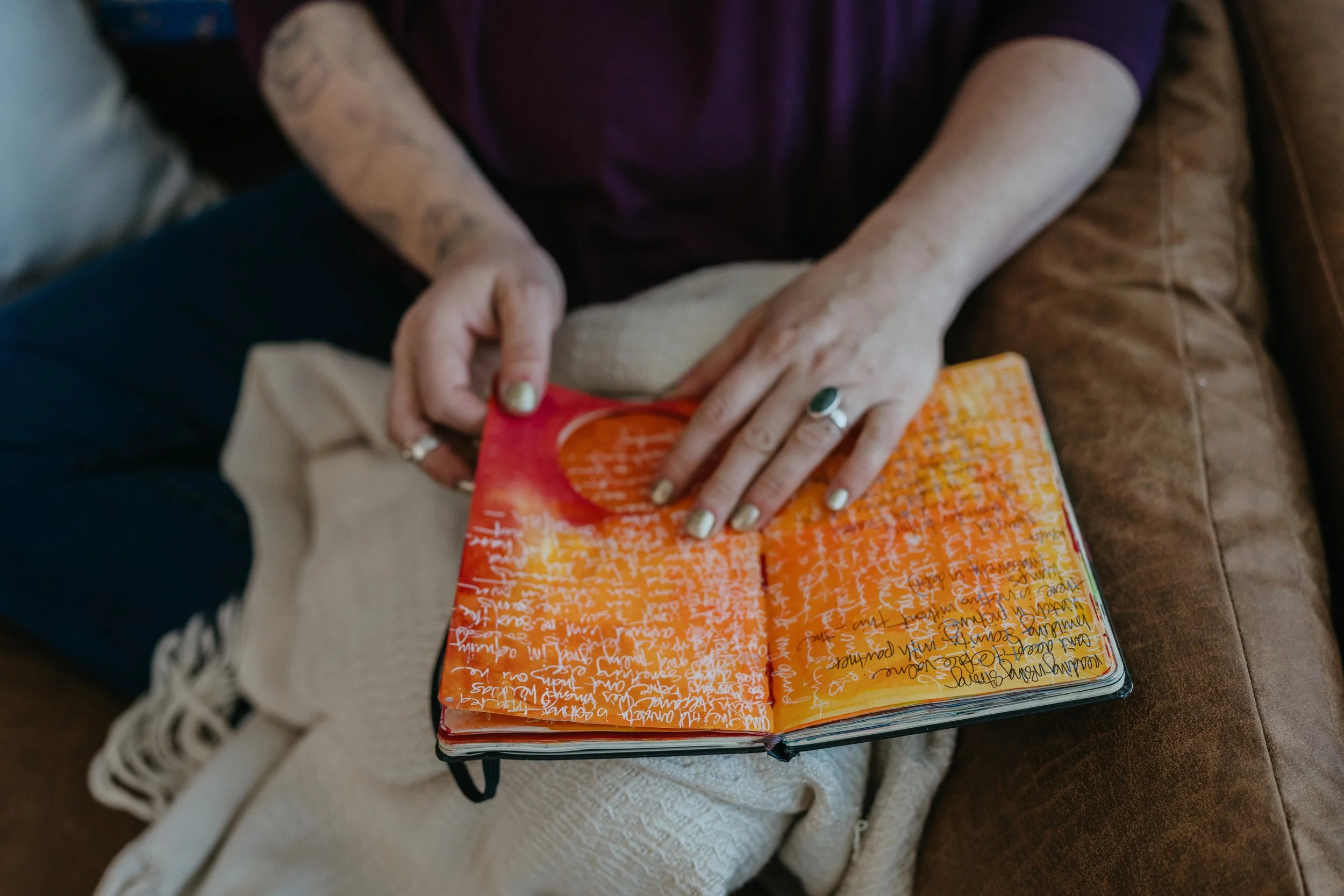 woman sitting on a couch with a blanket and journal