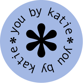 Circular logo with light blue background and black text reading 'You by Katie *' around a black asterisk in the center.