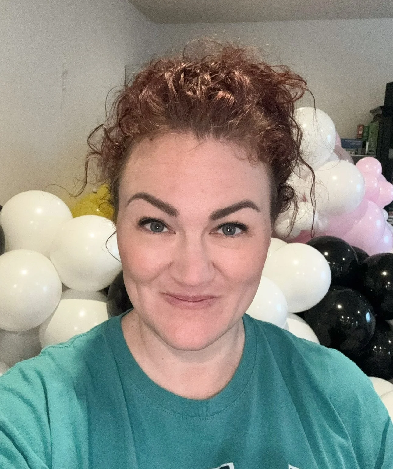 Photo of Nicole Wilcox, owner of Cascade Balloons, in front of a large cluster of white, pink, and black balloons.