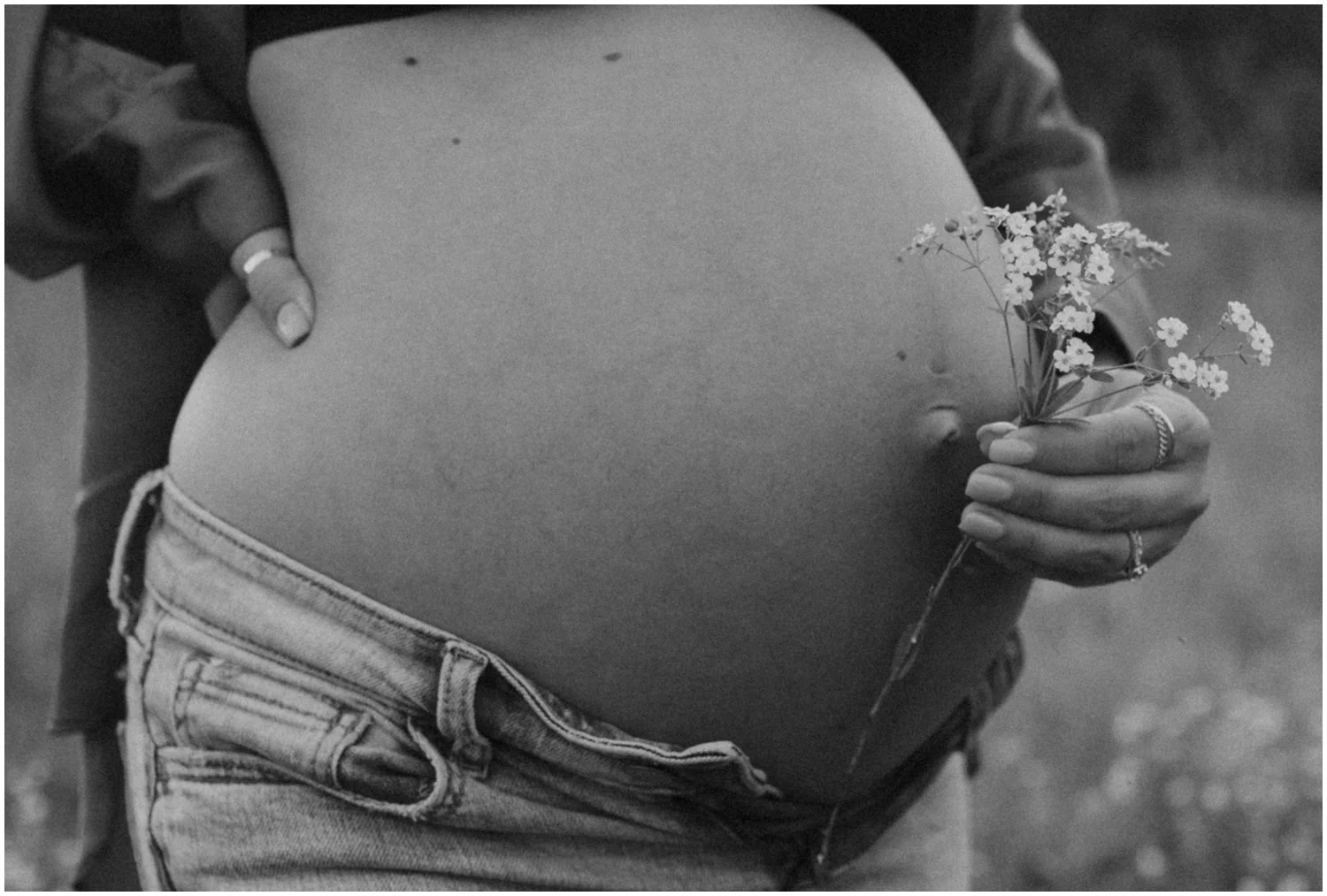 close up of woman holding white flowers in front of pregnant belly  for maternity session in wisconsin rapids