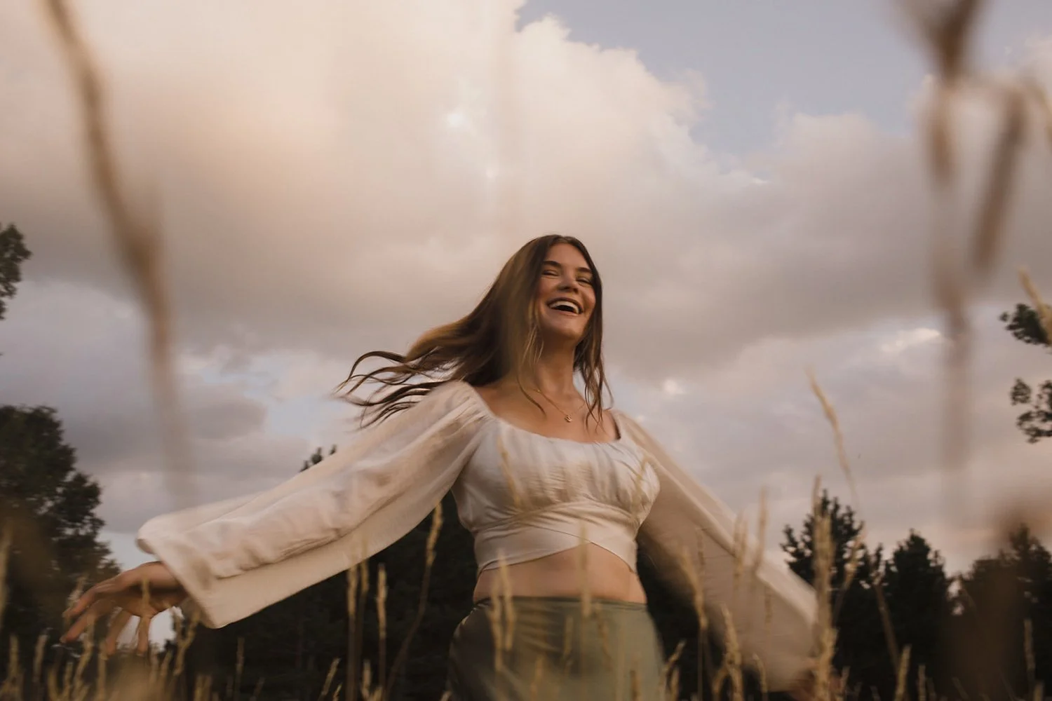teenage girl twirling in a field while laughing for her outdoor senior session in wisconsin rapids