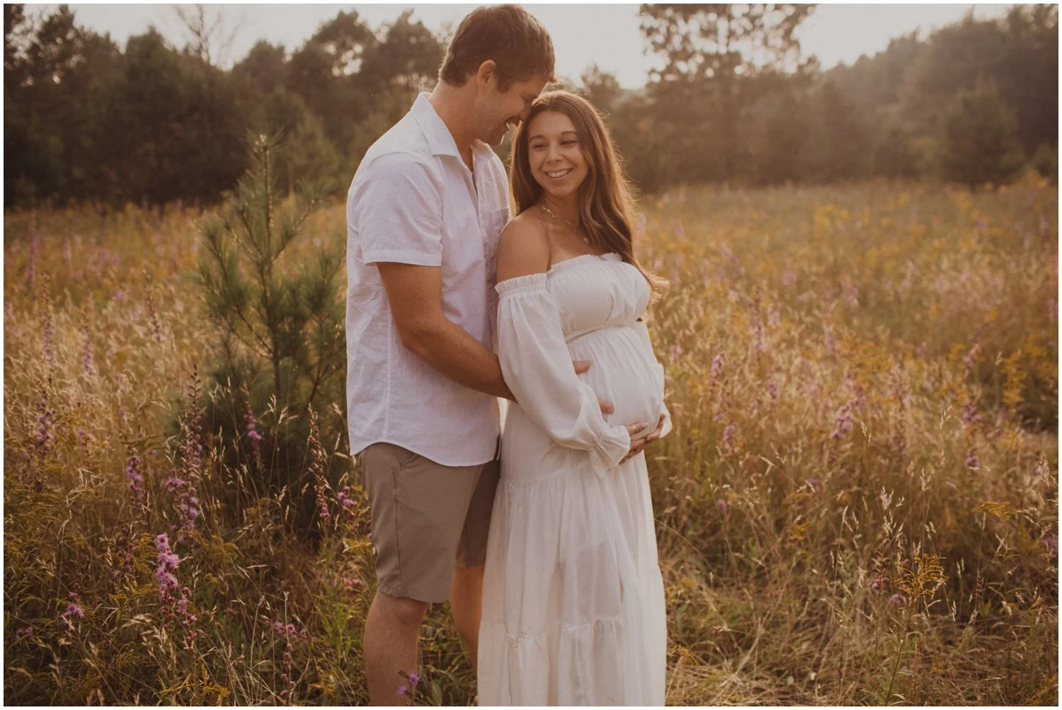 man and pregnant woman wearing white and standing in field of flowers for maternity session in wisconsin rapids