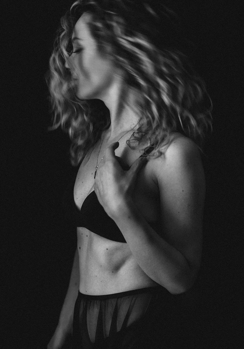 Expressive portrait photography capturing natural hair flow and movement with dramatic black and white lighting