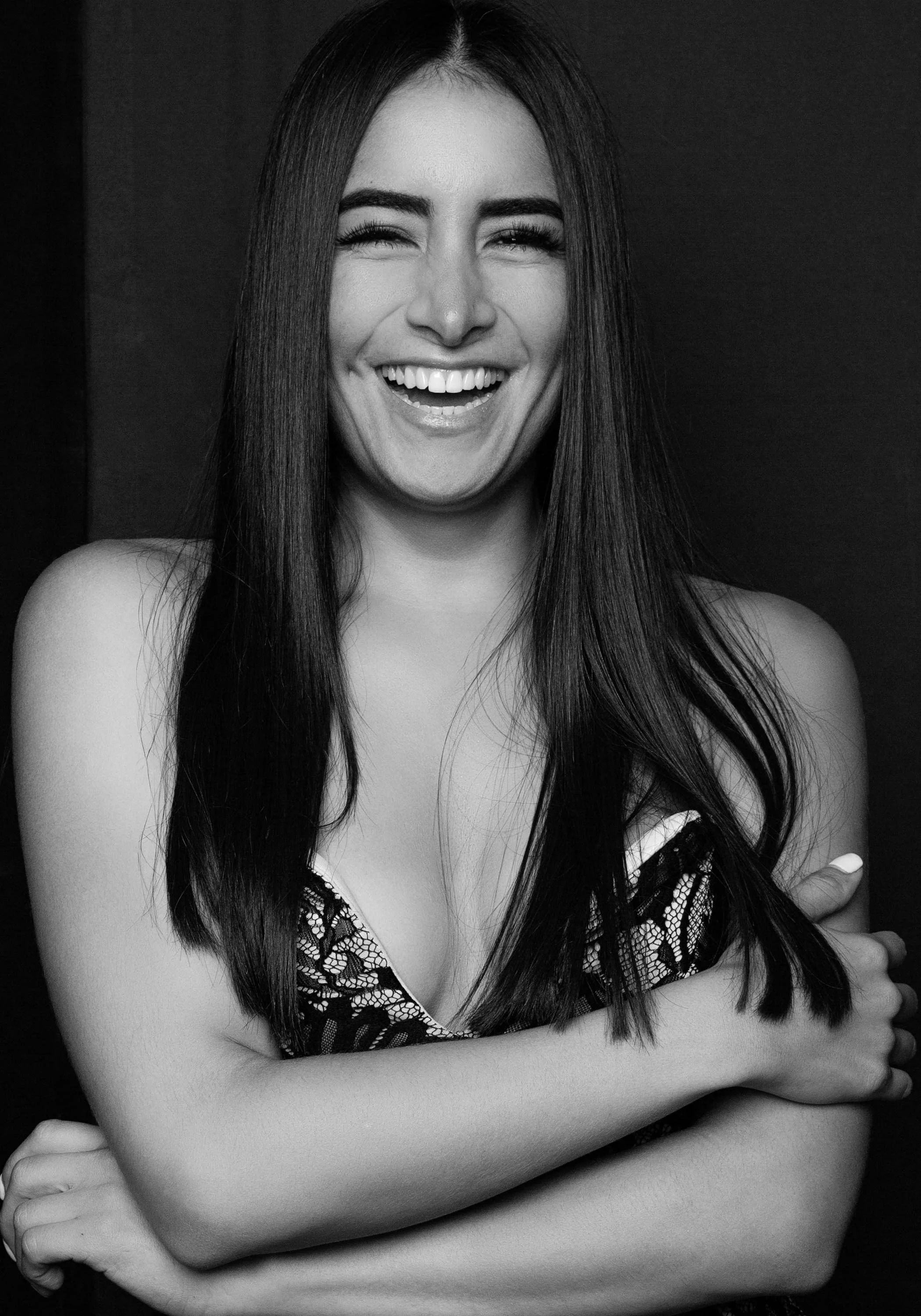 Black and white portrait of a woman laughing with long dark hair, full of joy and confidence.