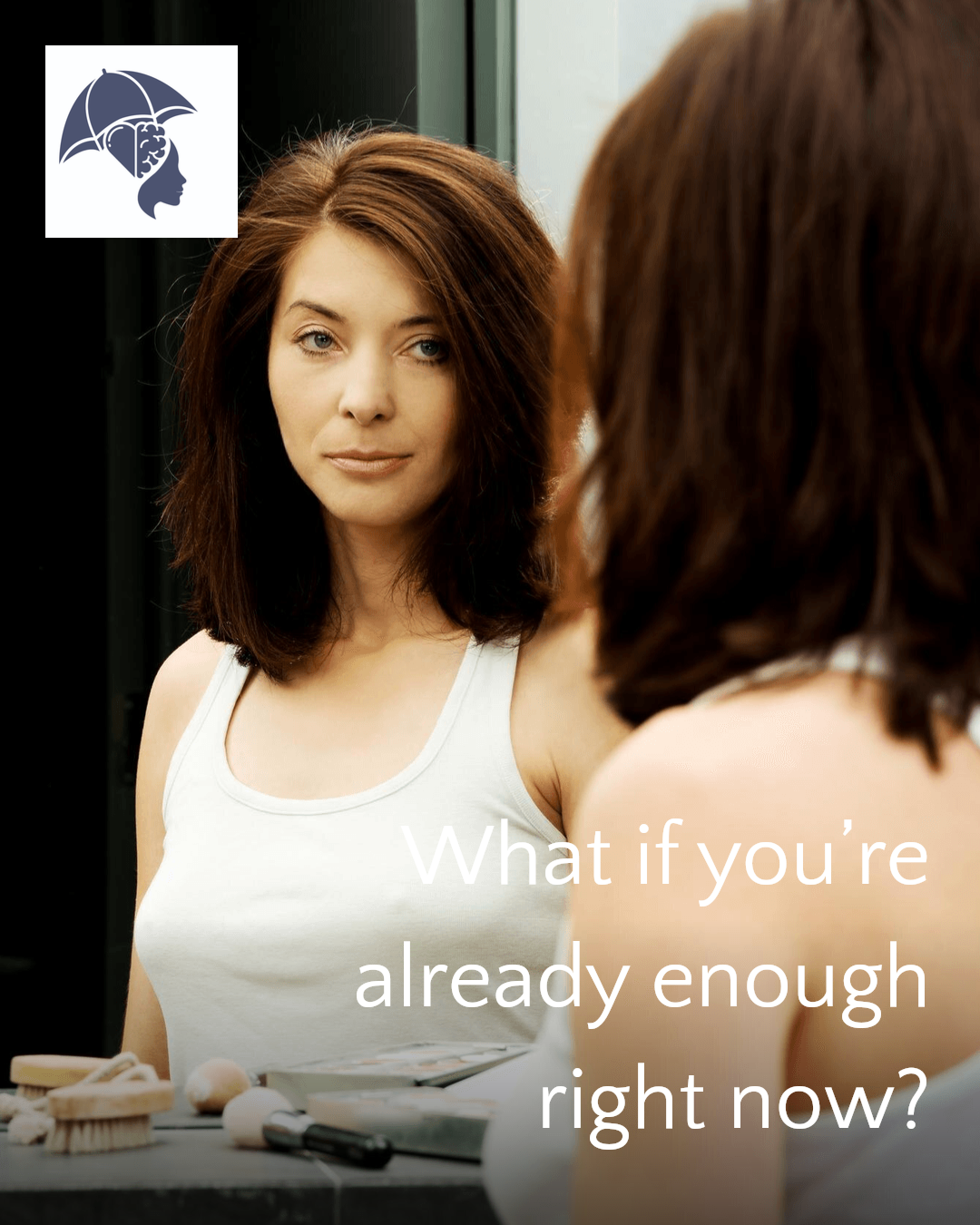 A woman with brown hair looking at her reflection in a mirror, wearing a white tank top, with makeup and skincare products on the table in front of her. The overlay text says, 'What if you're already enough right now?'