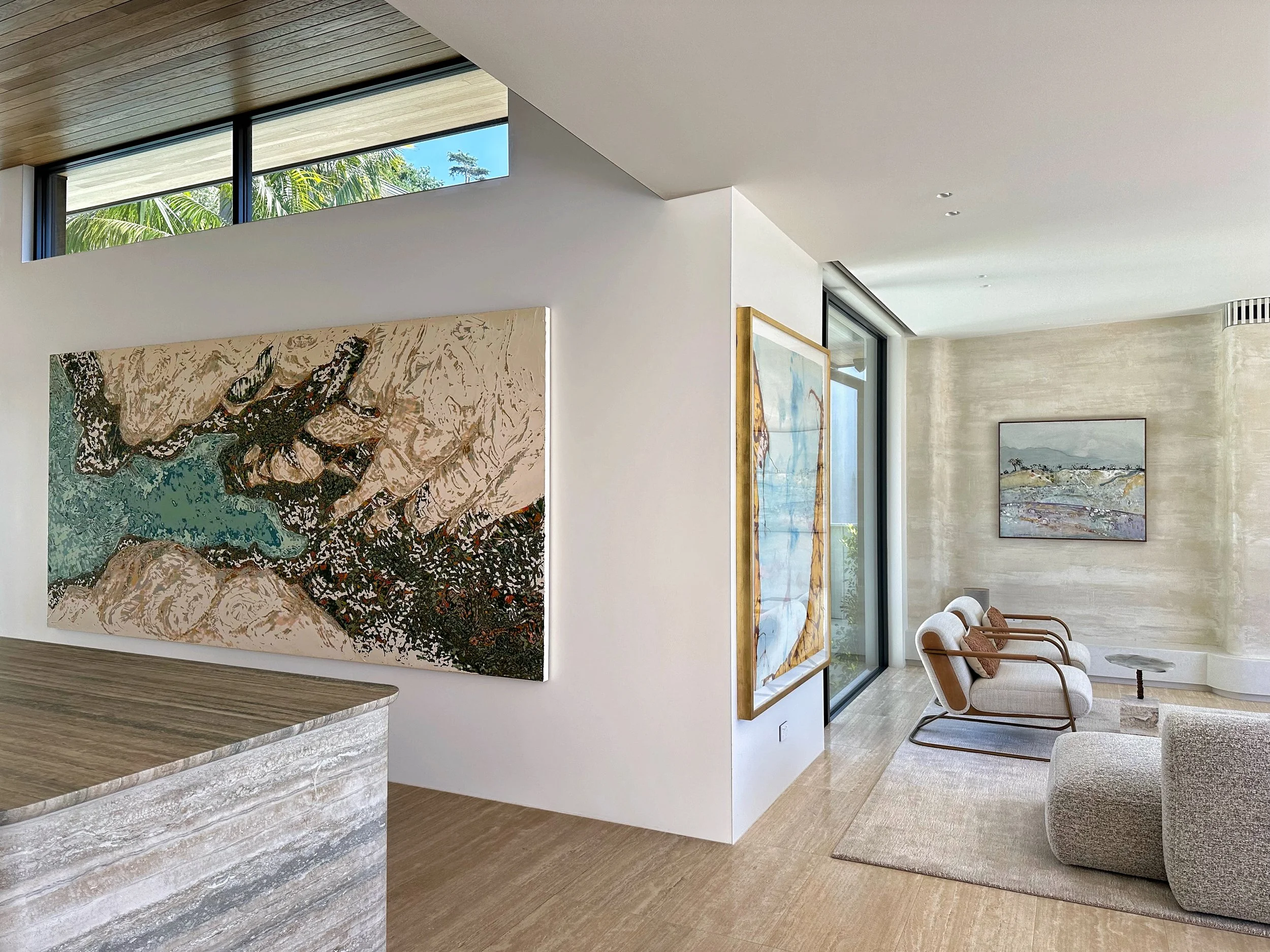 Modern interior living room with large windows, commissioned artwork by Korynn Morrison, beige chairs, and a light-colored carpet.