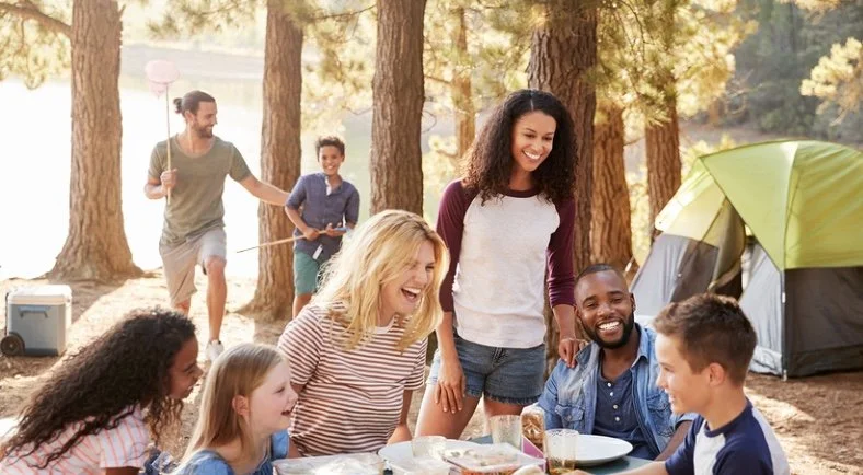 Diverse family group enjoying a meal together at a campsite. Represents connection, bonding, and healing through family therapy.
