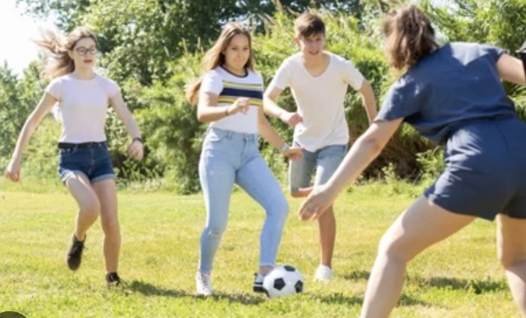 Group of preteens playing soccer outdoors on a sunny day. Represents social growth, emotional confidence, and positive outcomes from child therapy.