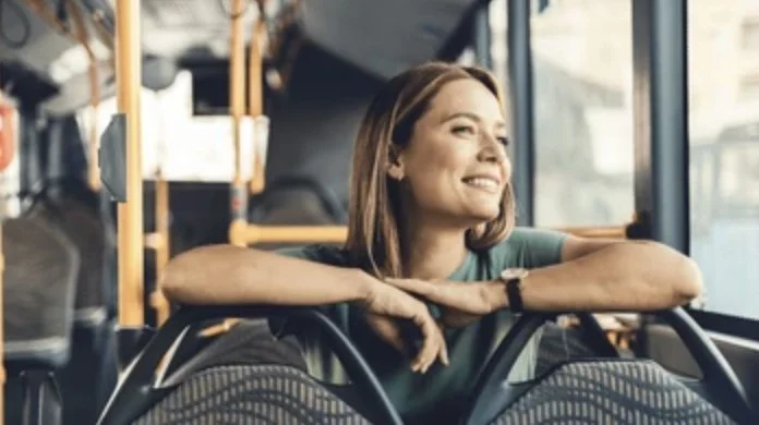 Smiling woman sitting calmly on a city bus, looking out the window. Symbolizes recovery and freedom from panic disorder in everyday life.