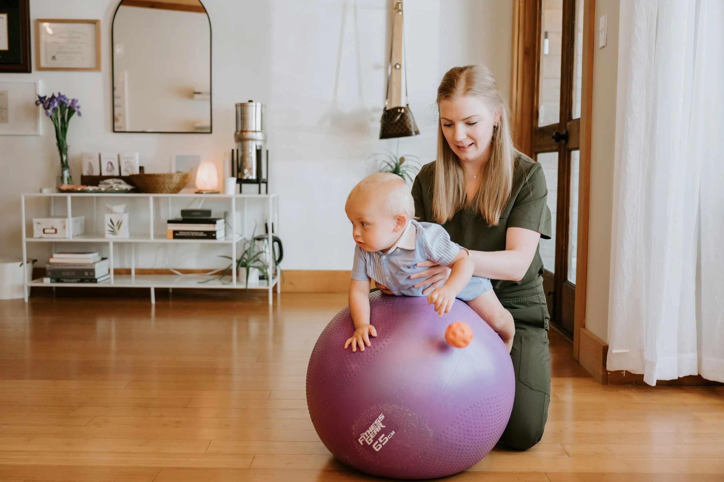 Pediatric chiropractor performing tummy time exercises with baby on exercise ball