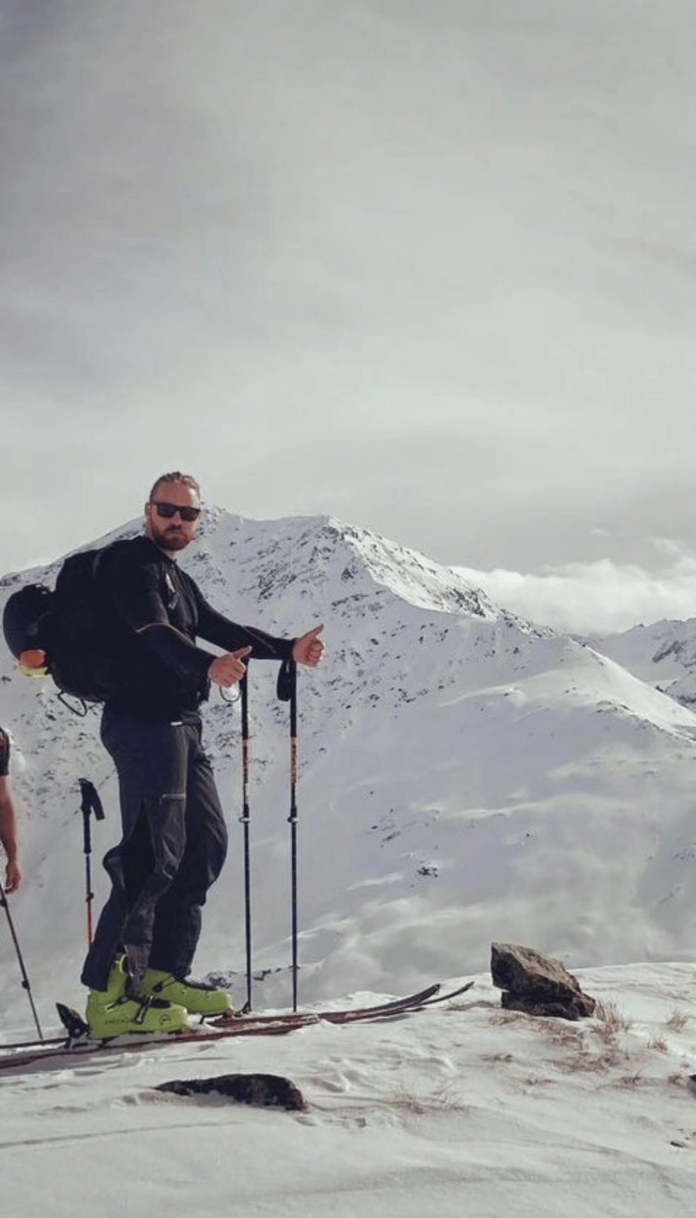 Jamie owner of jj strength standing on the top of a mountain with skis on