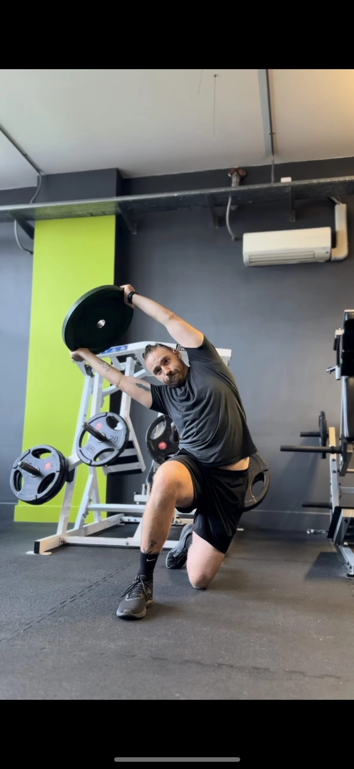 A man doing a workout using a weight plate in a gym. Best personal trainer in Oxford. Best personal trainer near me.