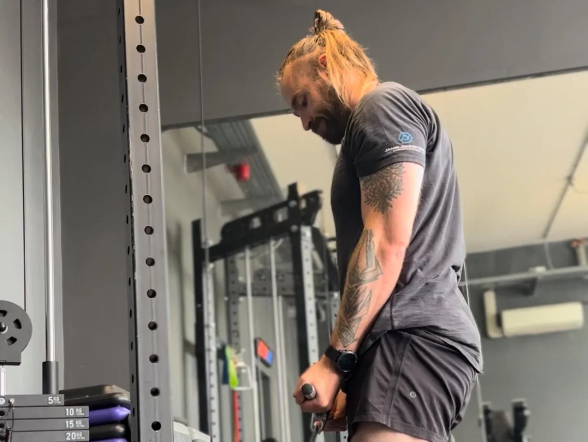 Jamie, owner of JJ Strength performing a bicep curl cable exercise in his personal training gym in oxford
