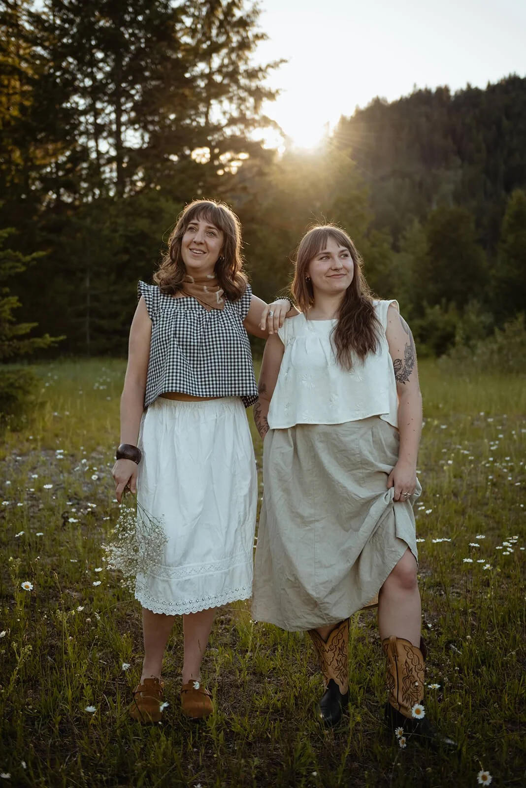 Two women standing in a grassy field with daisies, wearing the Diane crop made from deadstock fabric