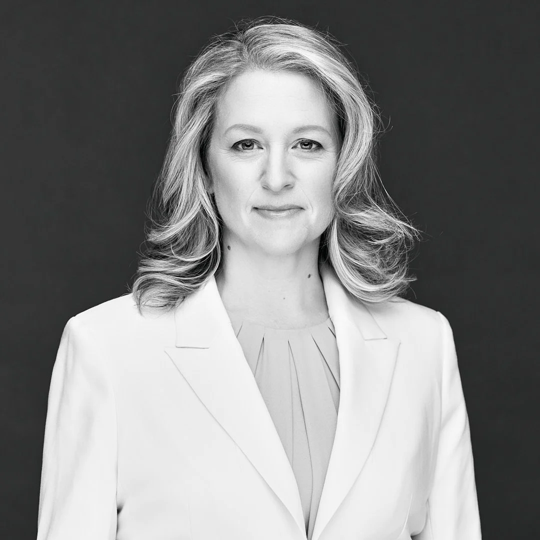 A black and white photo of Lisa. She looks directly at the camera and smiles. Her long hair is loose around her shoulders.
