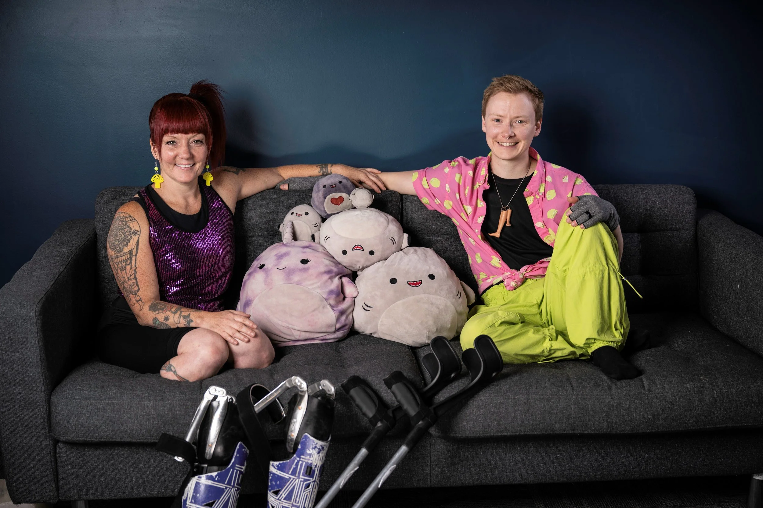 A Family portrait of Maxime and Erin, two white Disabled nonbinary neuro non0conformoing (neurodivergent) humans, sitting on a couch