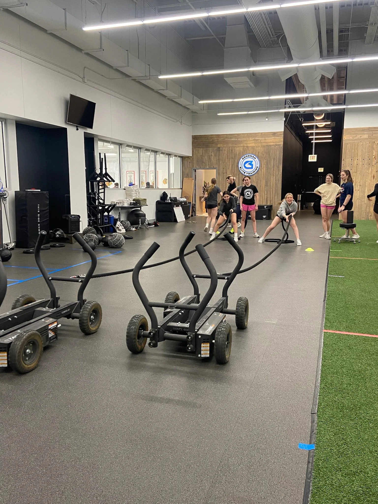 Indoor gym with workout equipment and a group of women exercising in the background.