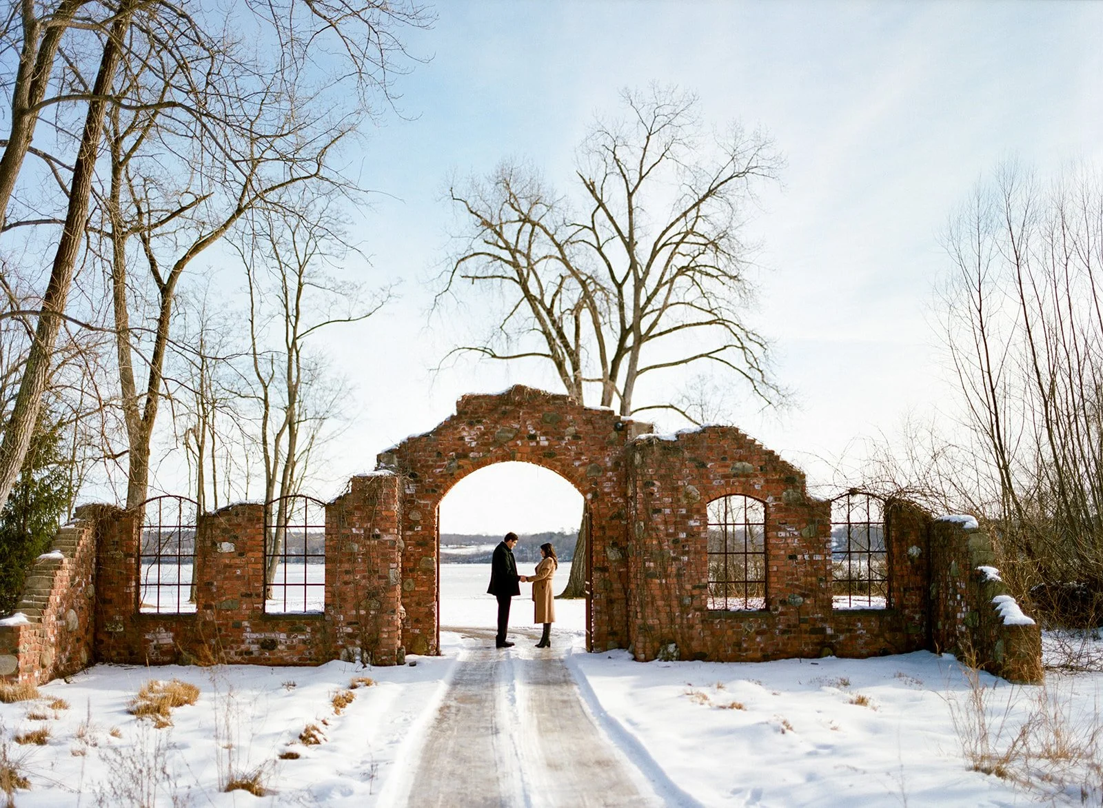 Couple holding hands in the snow underneath the Ruins at Hutton Brickyards
