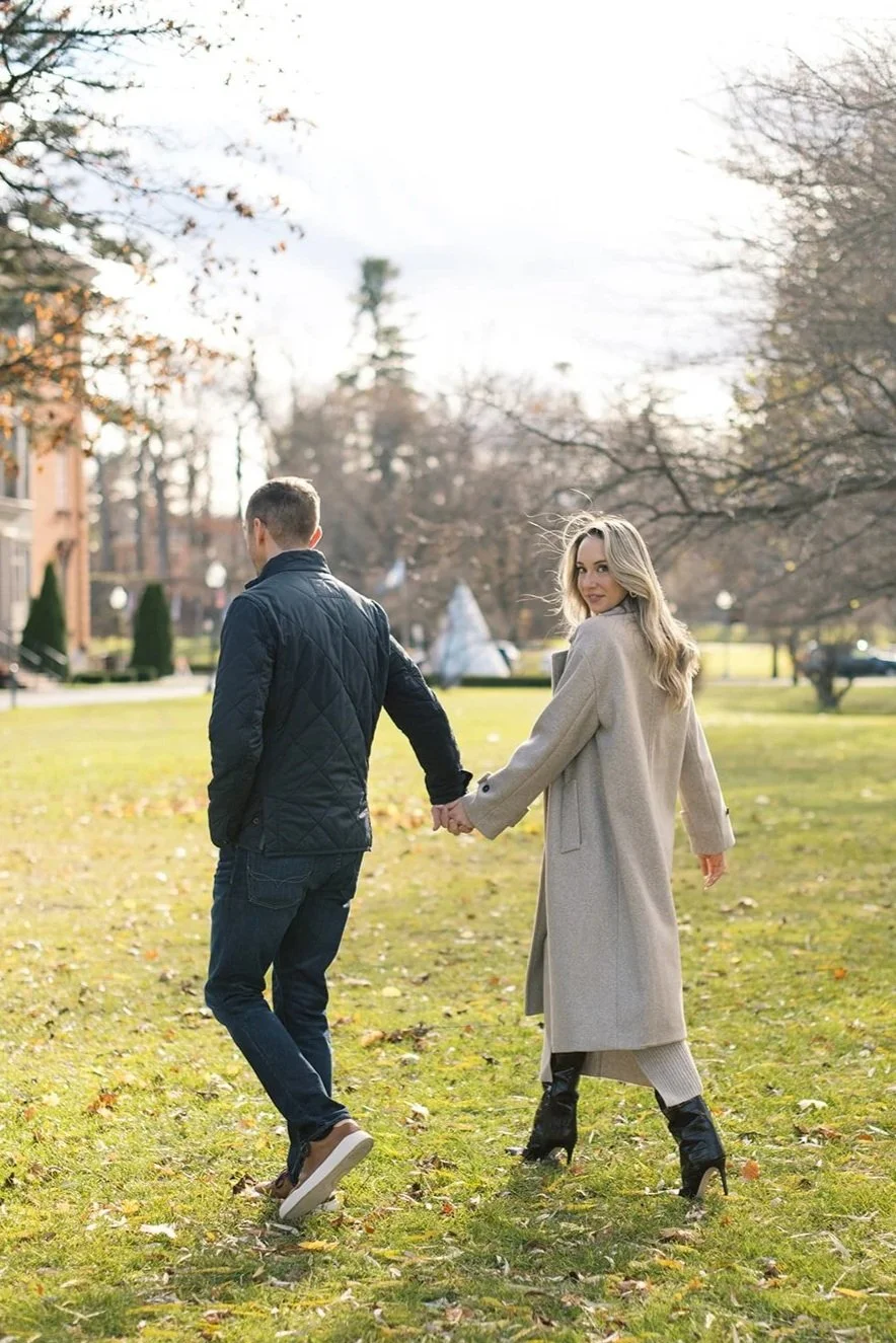 Couple walking together in Saratoga Springs. Woman is looking over her shoulder at the camera.