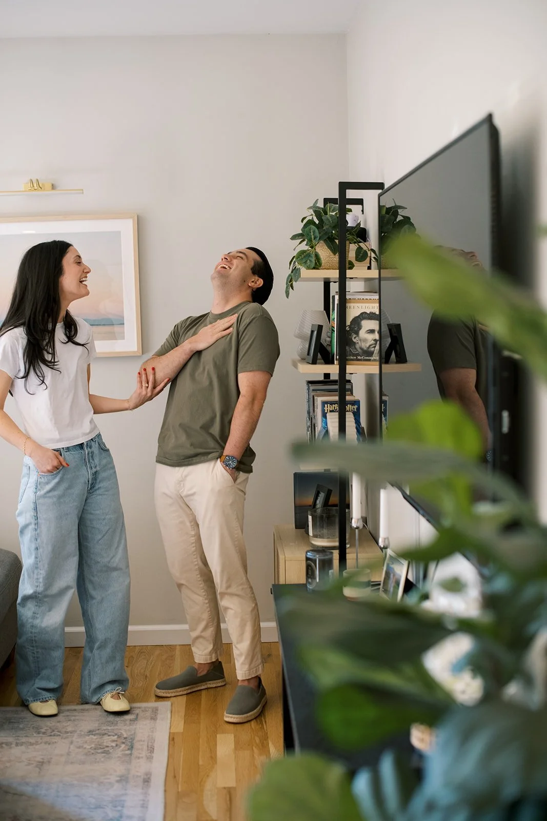 couple laughing heavily, standing in their apartment  