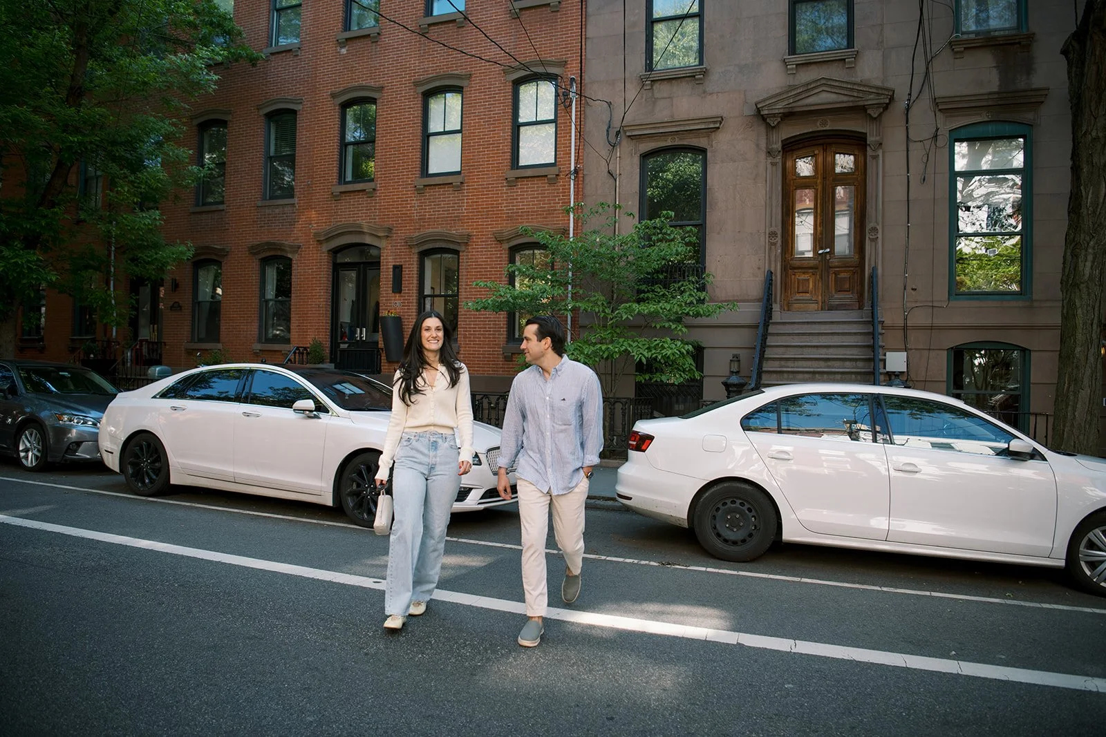  couple laughing as they walk across a street in Hoboken together 