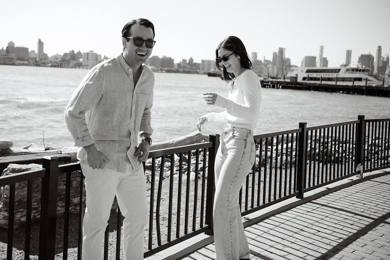 Laughing couple standing together overlooking the Hudson River and NYC skyline from Hoboken, NJ