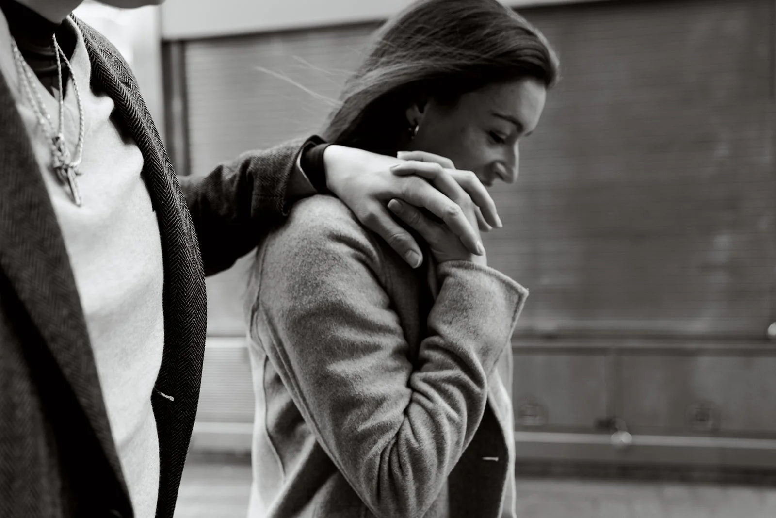 black and white image of woman holding her partners hand as it rests on her shoulder