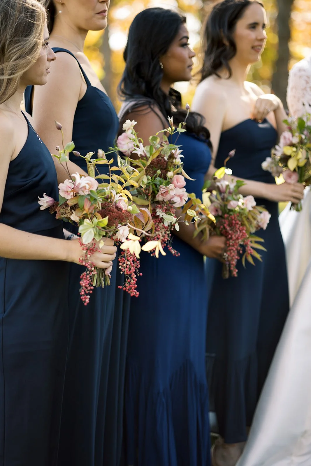 wedding party wearing navy blue dresses and holding mauve, pink, and green wildflower bouquets