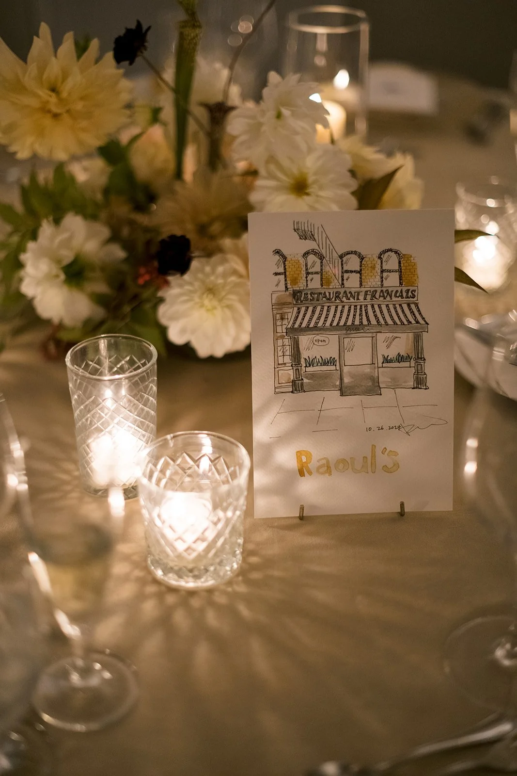 wedding table sign of handpainted restaurant against floral centerpiece and votive candles