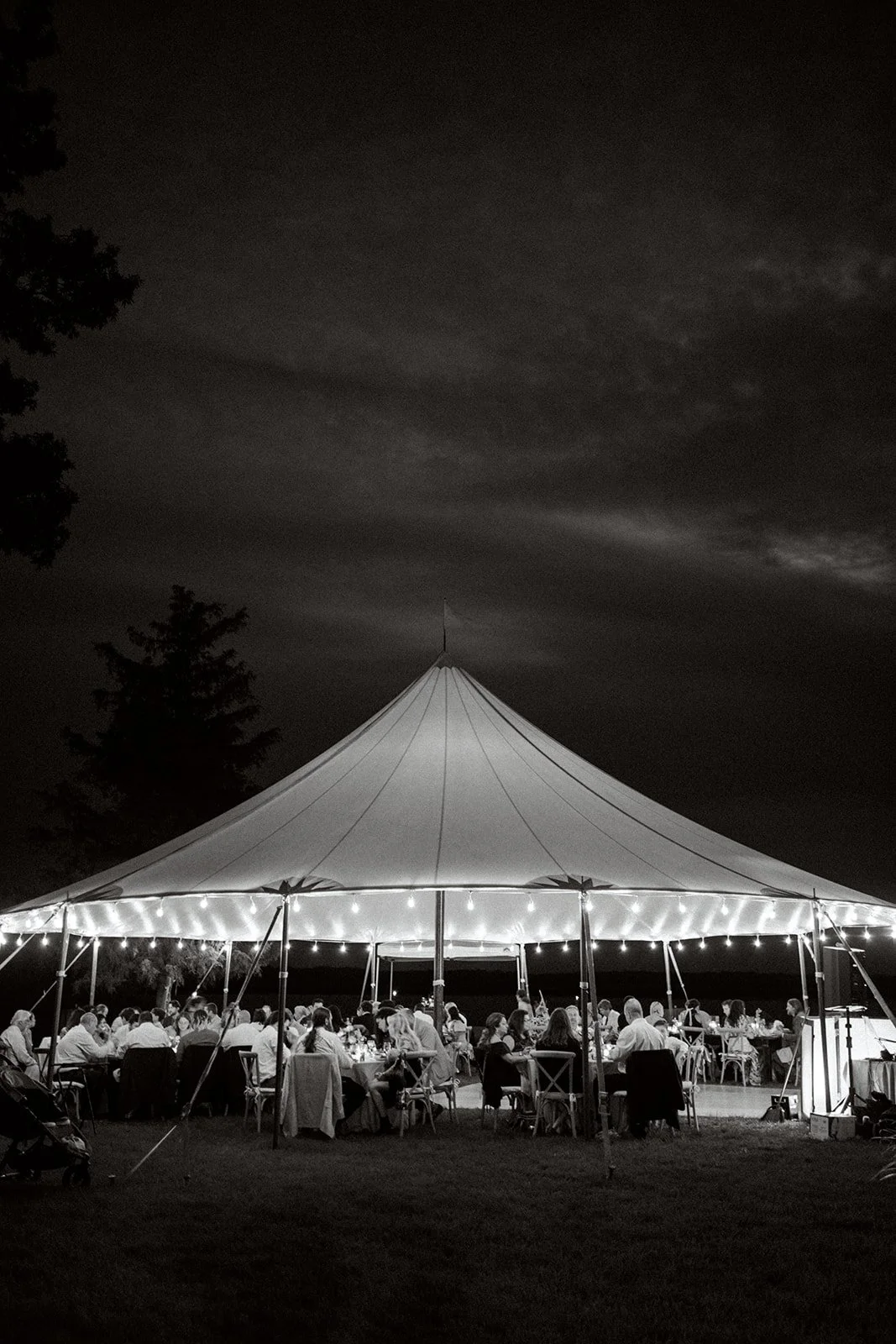 night photo of sperry tent with string lights and guests at long tables