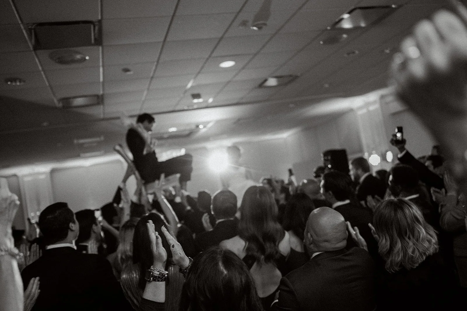 bride and groom lifted in chairs during the hora. blurry image