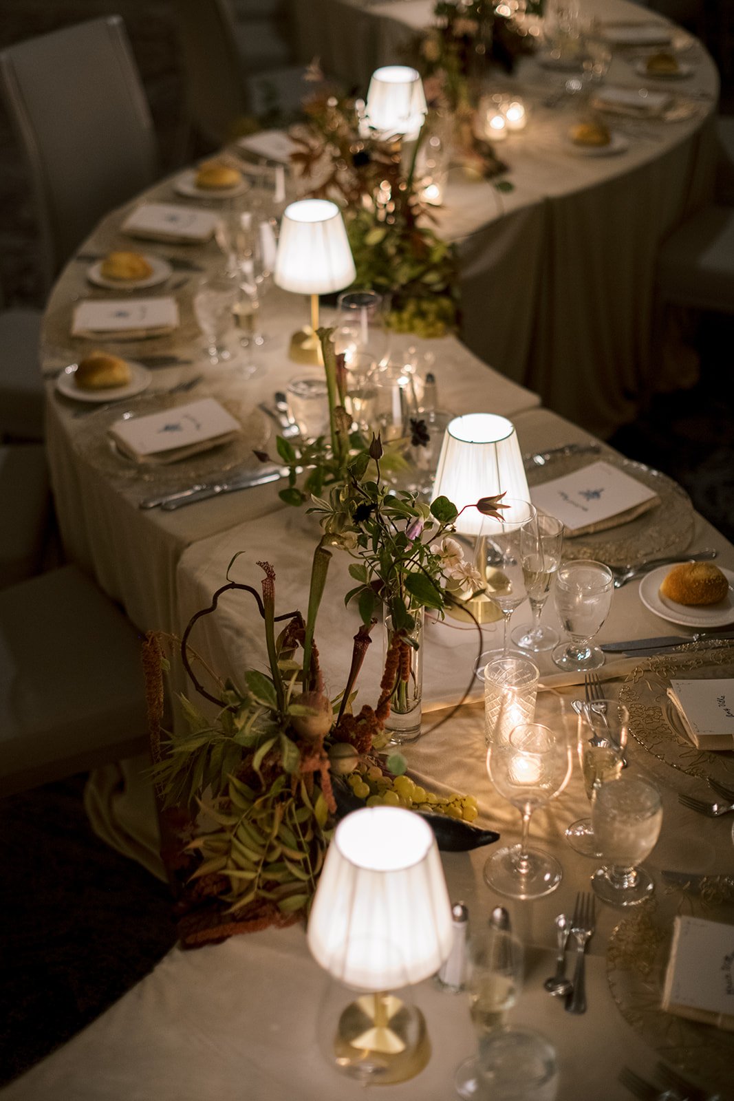 serpentine wedding reception table with small tabletop lamps