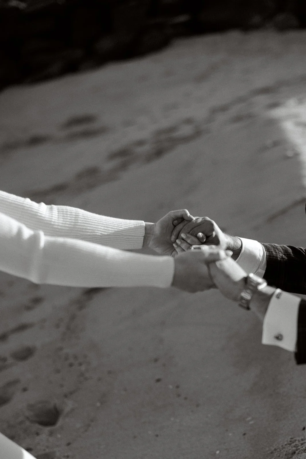 Black amd white image. Hands pulling each other together. Beach setting