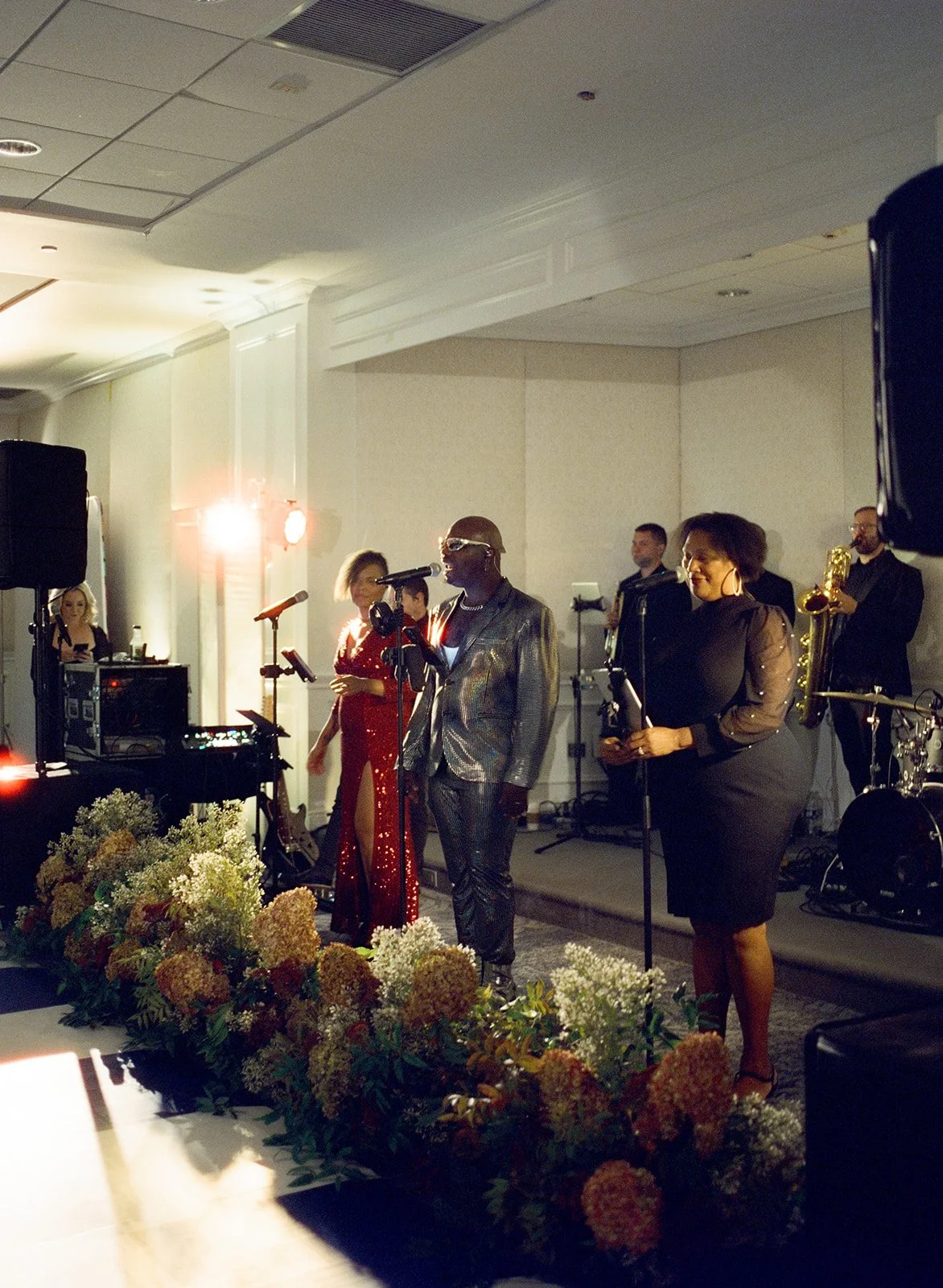 Atomic Funk Project band lead singers standing behind large floral bouquets on a stage