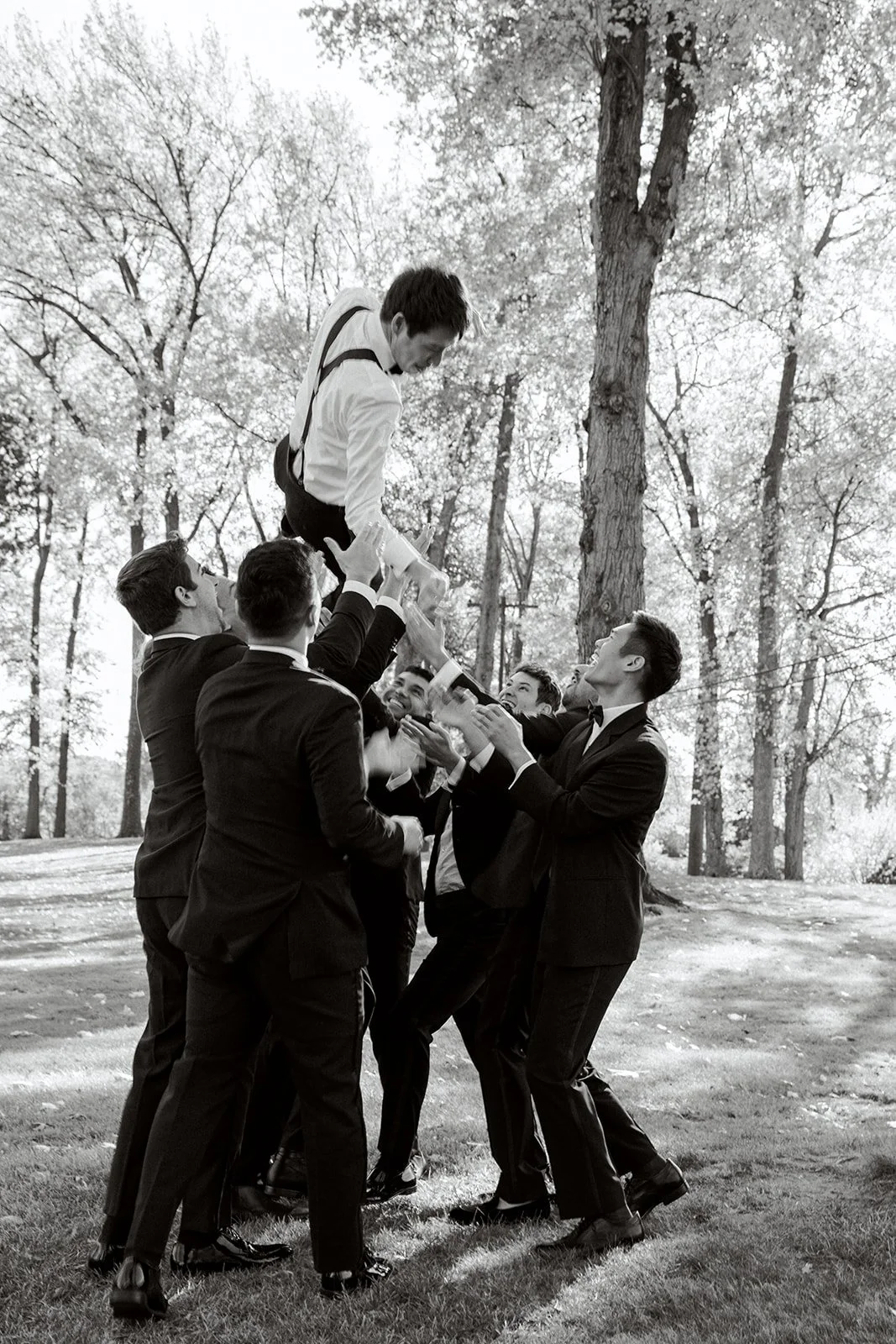 groomsmen tossing groom into the air