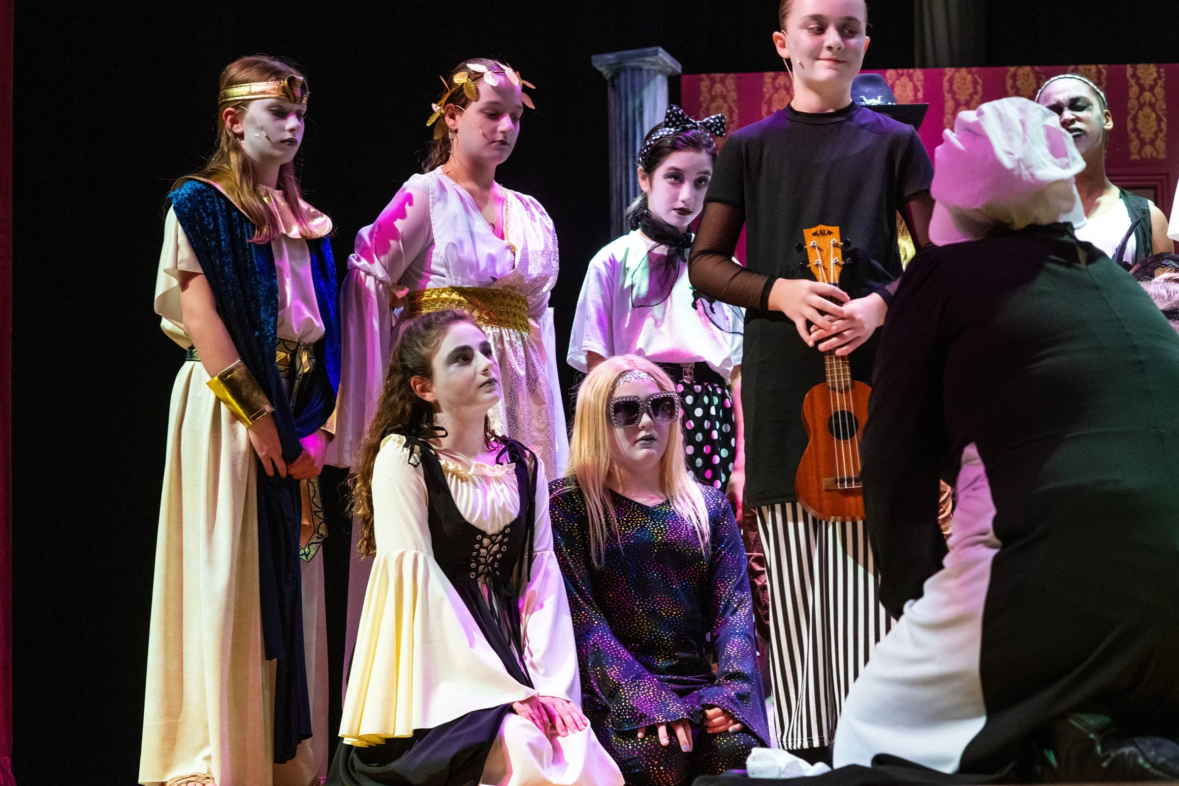 Children dressed in costumes performing on stage during a theatrical play.