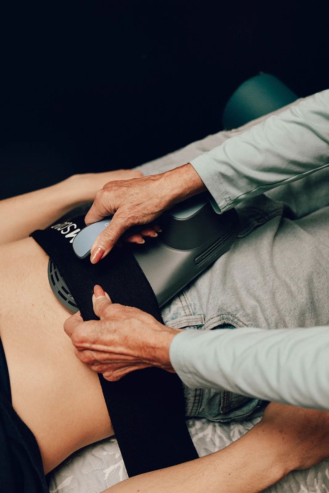 Edna placing Emsculpt Neo padde on abdomen of a client.