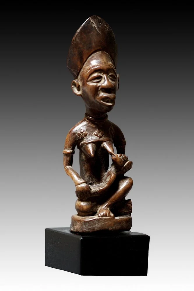 Yombe maternity figure, the mother is seated in a lotus position wearing a mitre-shaped crown.  www.gallerytribalart.com