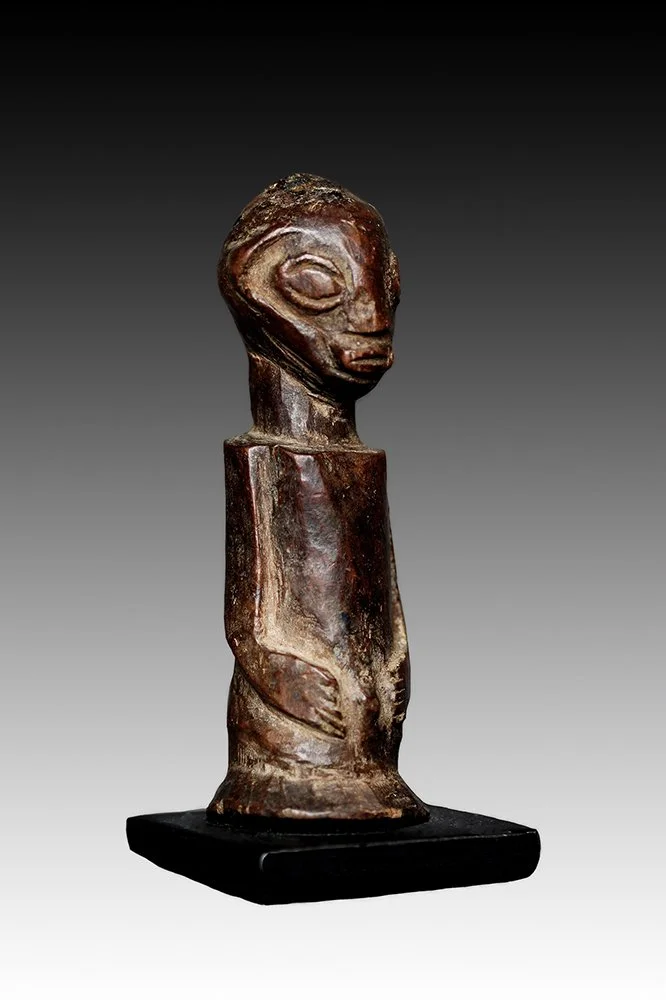Luba fetish has wedged fingers and hands resting on the abdomen.  www.gallerytribalart.com