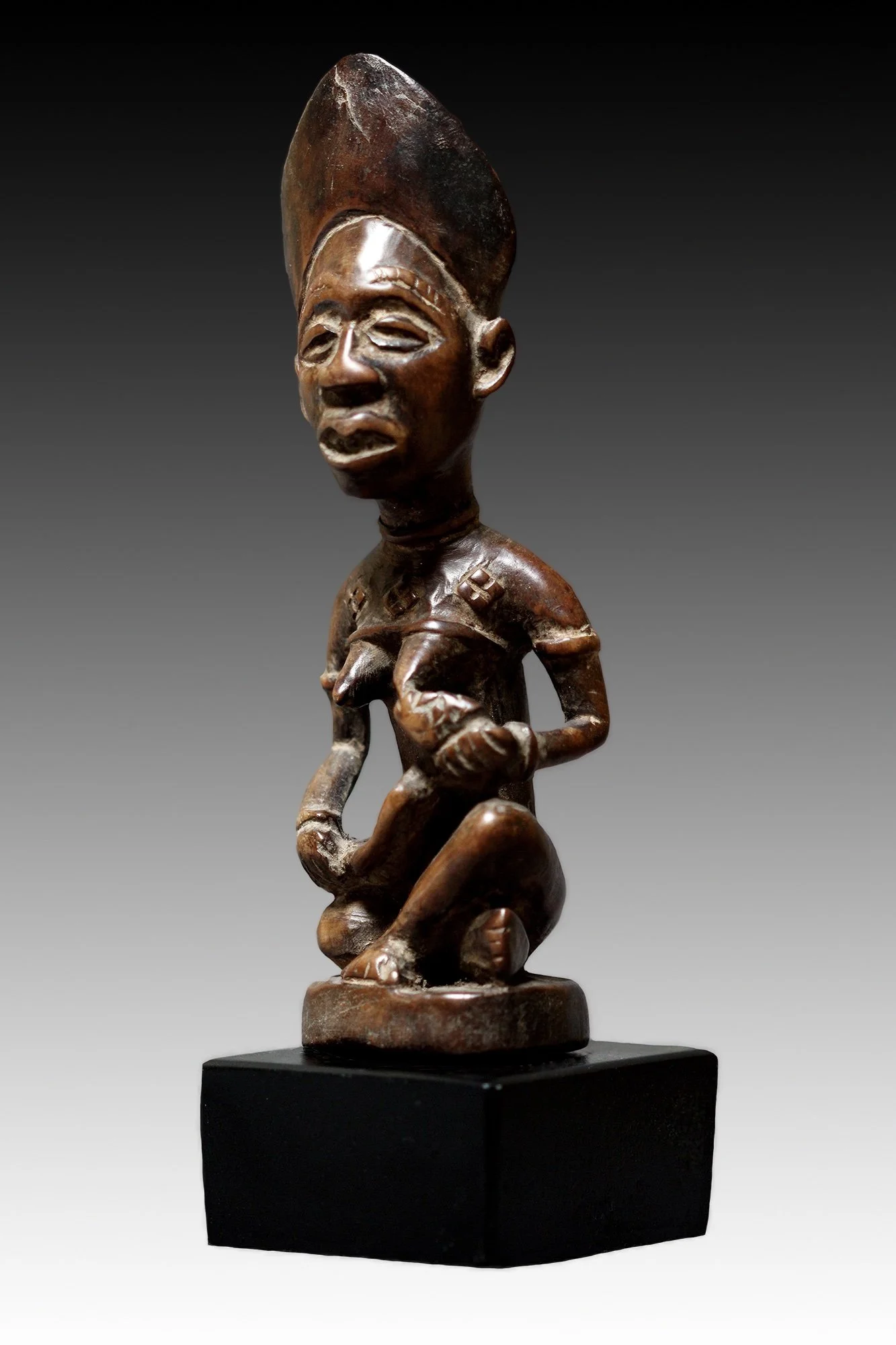 Yombe maternity figure, the nursing child is held by the mother’s clasping hands, the infant’s body conforms to the arc of the mother’s lap.  www.gallerytribalart.com