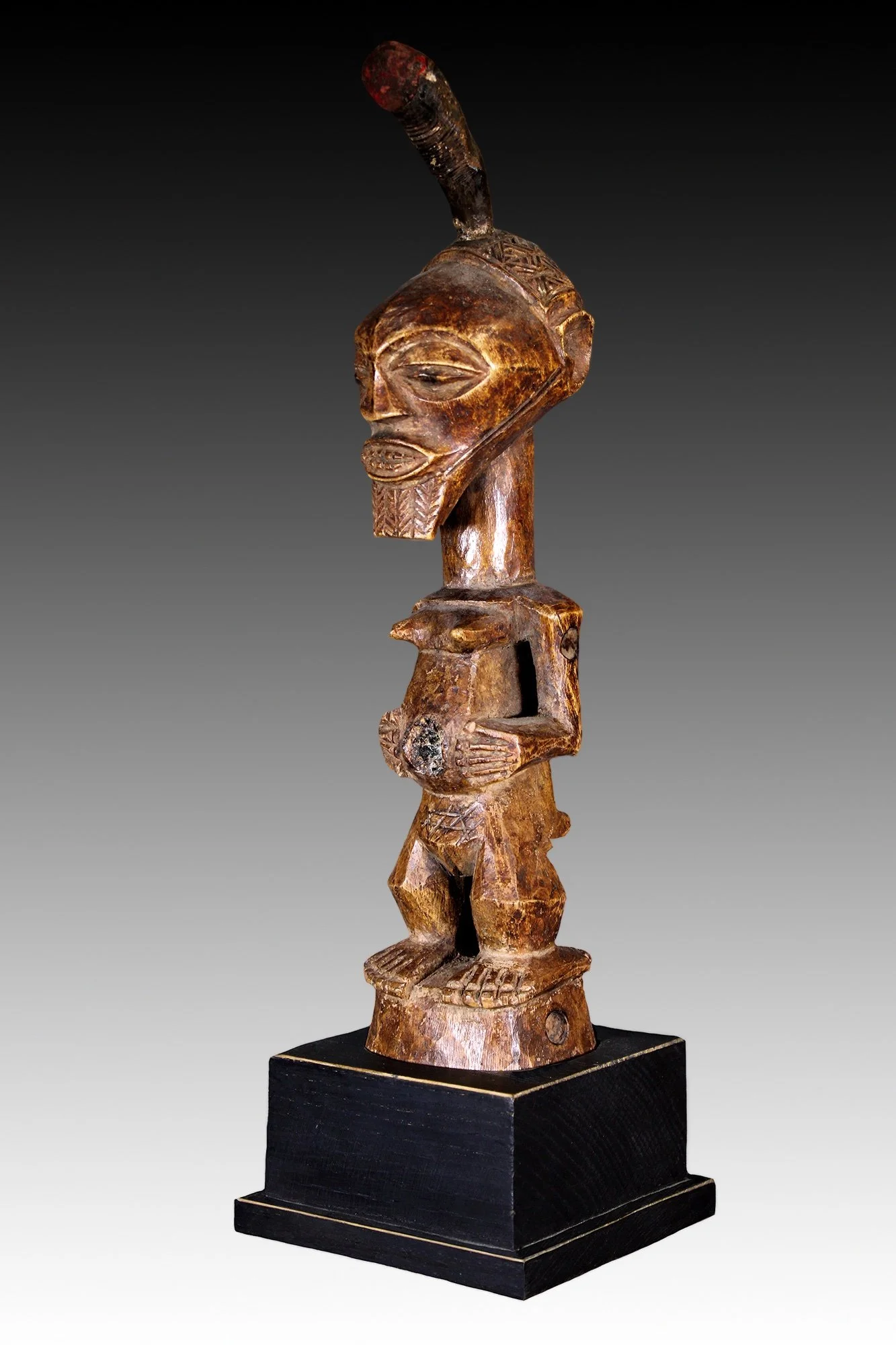Songye figure, has an animal horn atop it’s head with red cloth and an abdominal cavity with glass.  www.gallerytribalart.com