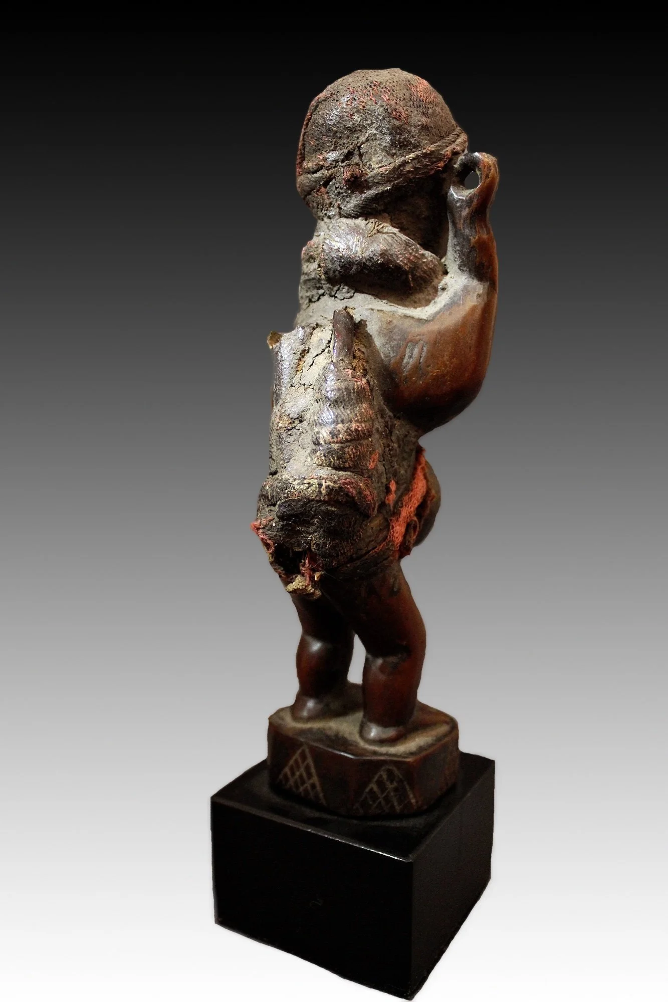 Kongo figure, back view, has glass eyes, snake skin, animal horn, red fiber, collar and skull cap.  www.gallerytribalart.com