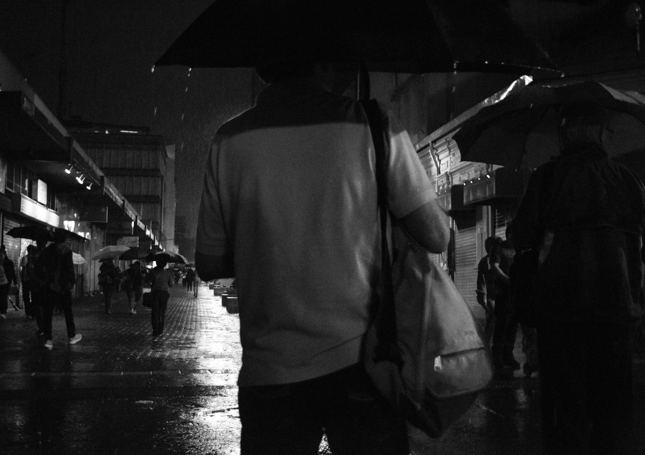 A man walks with an umbrella in the Central Avenue of San Jose.
