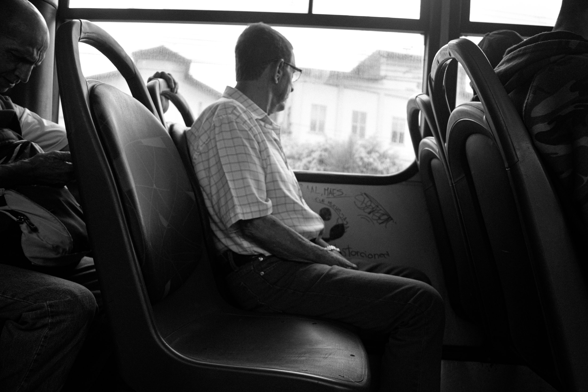 An eleder looking out the window on a bus ride to the center.