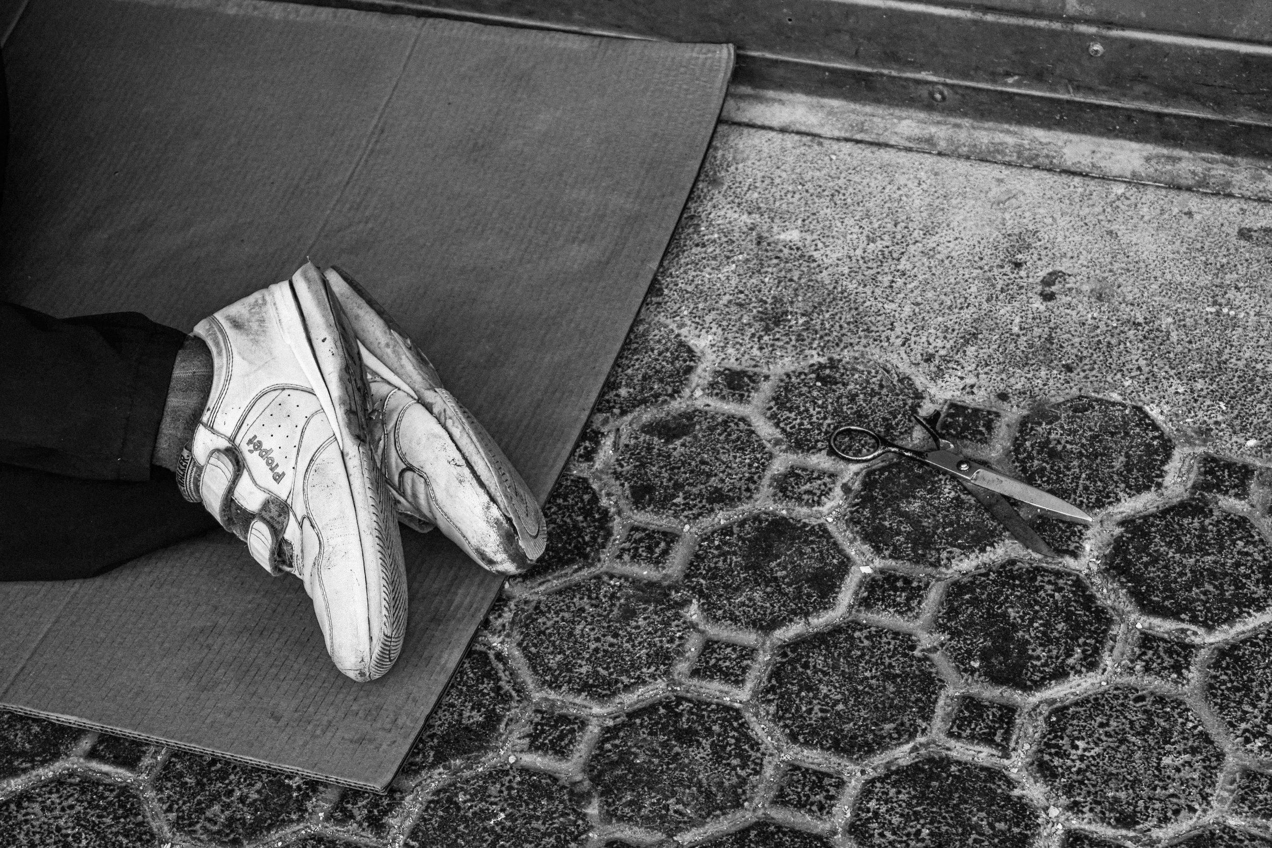 A man lies on a cardboard piece with a pair of scissors.
