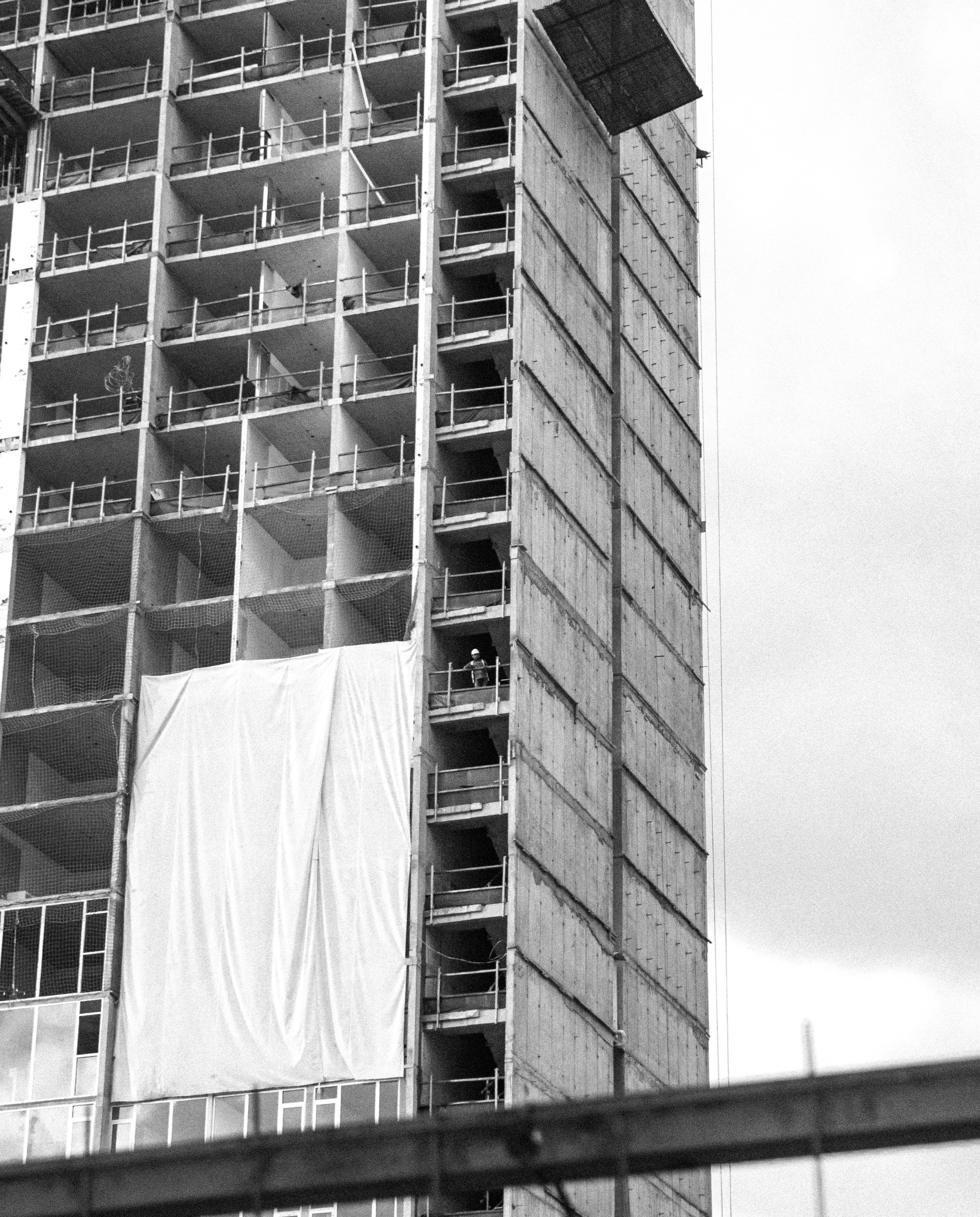A construction worker gazing at the city while taking a break on a soon to be residential building.